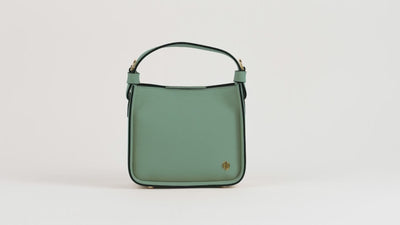 Mint-green Affinée leather handbag shown against a soft ivory background.